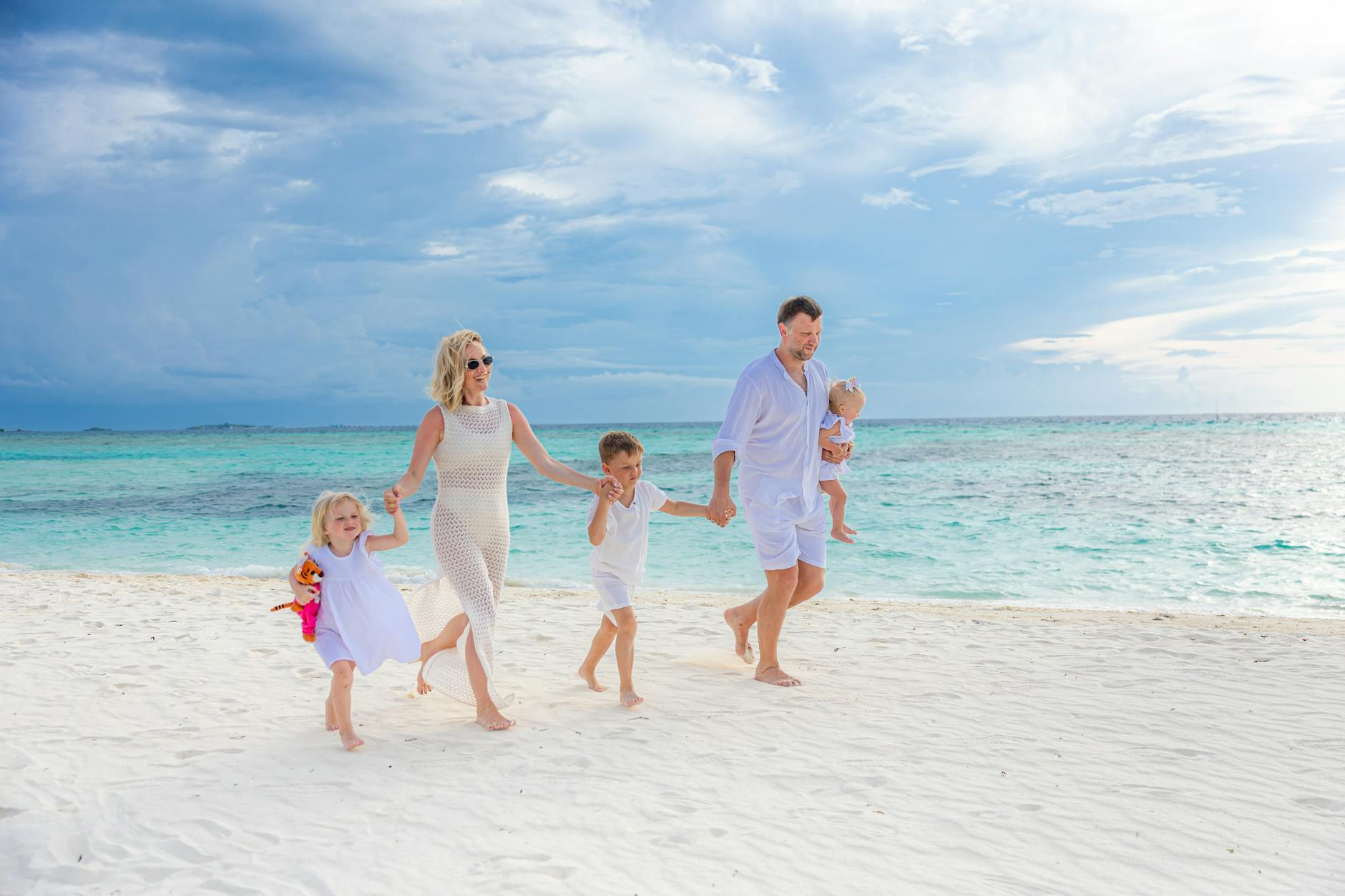 happy family strolling on a tropical beach | Travel agent for busy moms