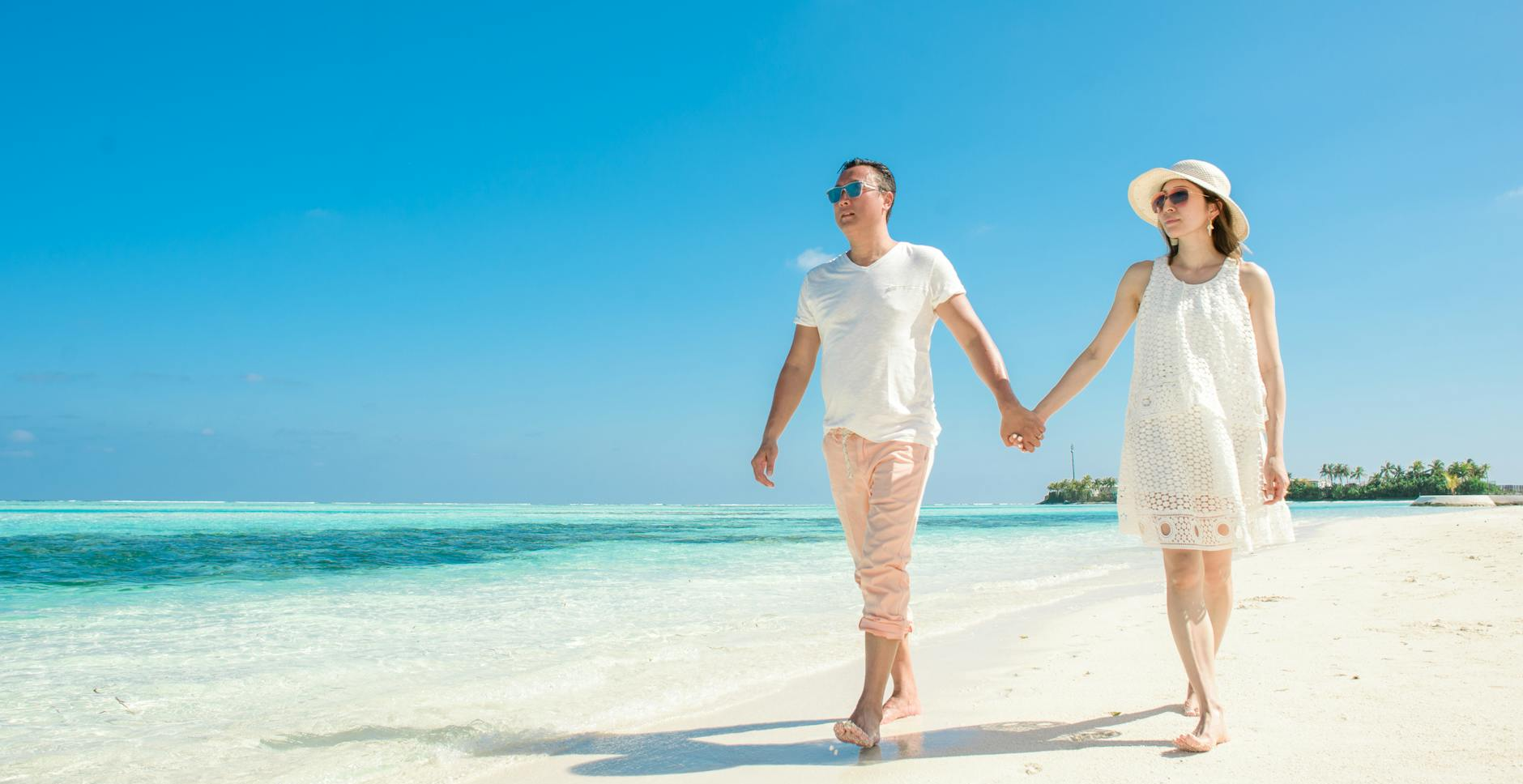 man and woman walking down the beach on a Honeymoon